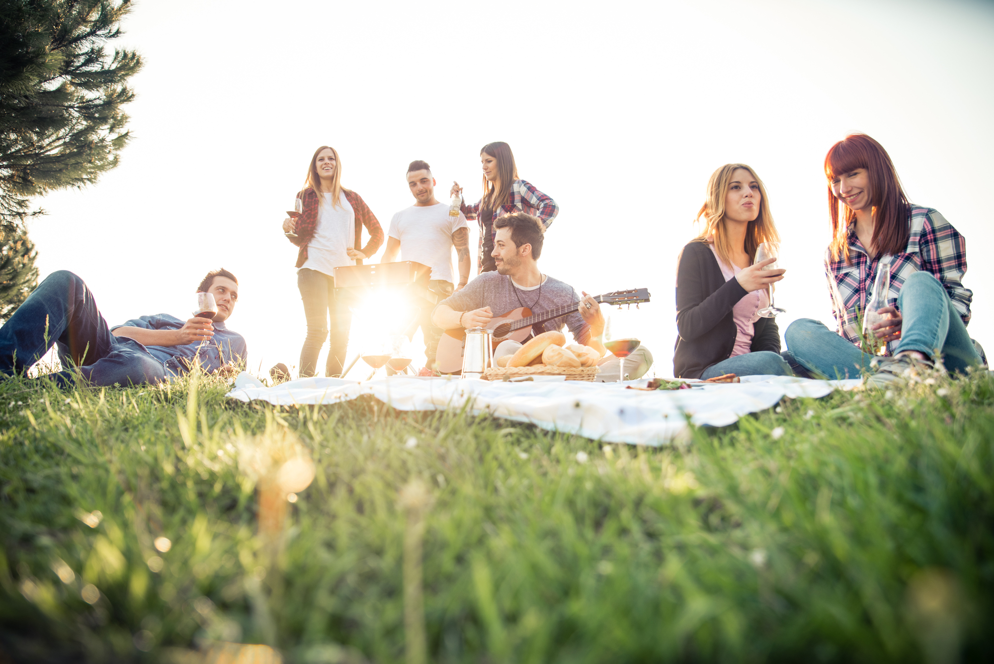 Group of friends outdoors playing the guitar and drinking wine