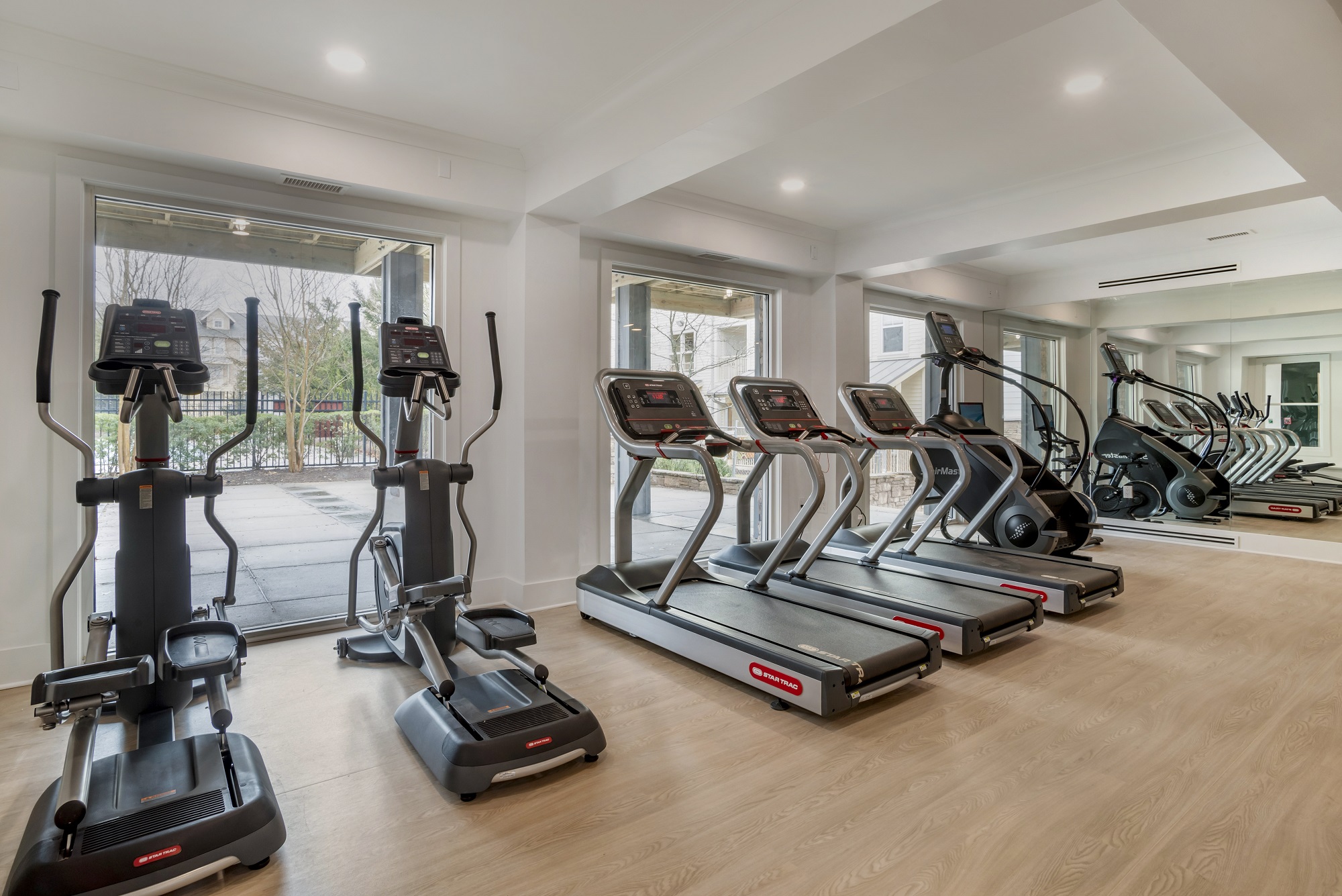 Indoor gym area with cardio machines, outdoor lighting, and wood-style flooring