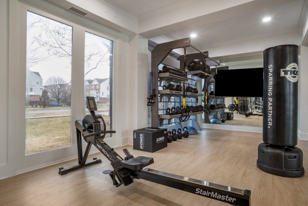 Indoor gym area with cardio machines, outdoor lighting, TV, and wood-style flooring