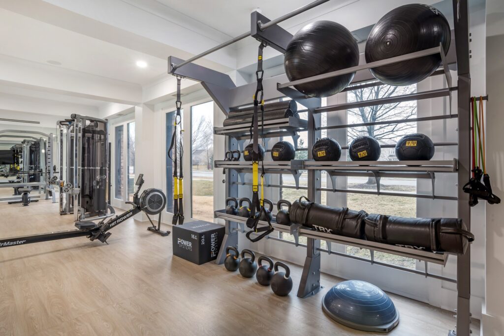 Indoor gym area with weights, medicine balls, outdoor lighting, and wood-style flooring