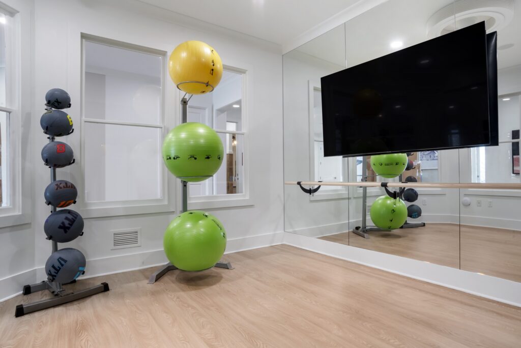 Indoor workout studio with medicine balls, large mirror, TV, and wood-style flooring