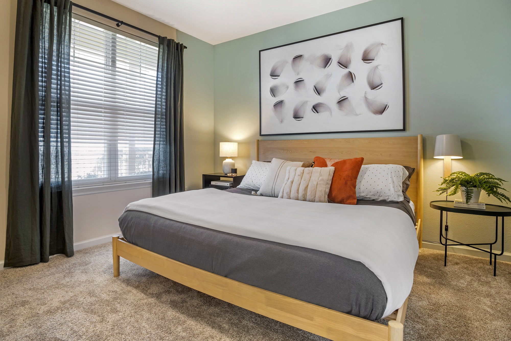 Bedroom with king size bed, accent colored walls, lamps, window, and carpet flooring