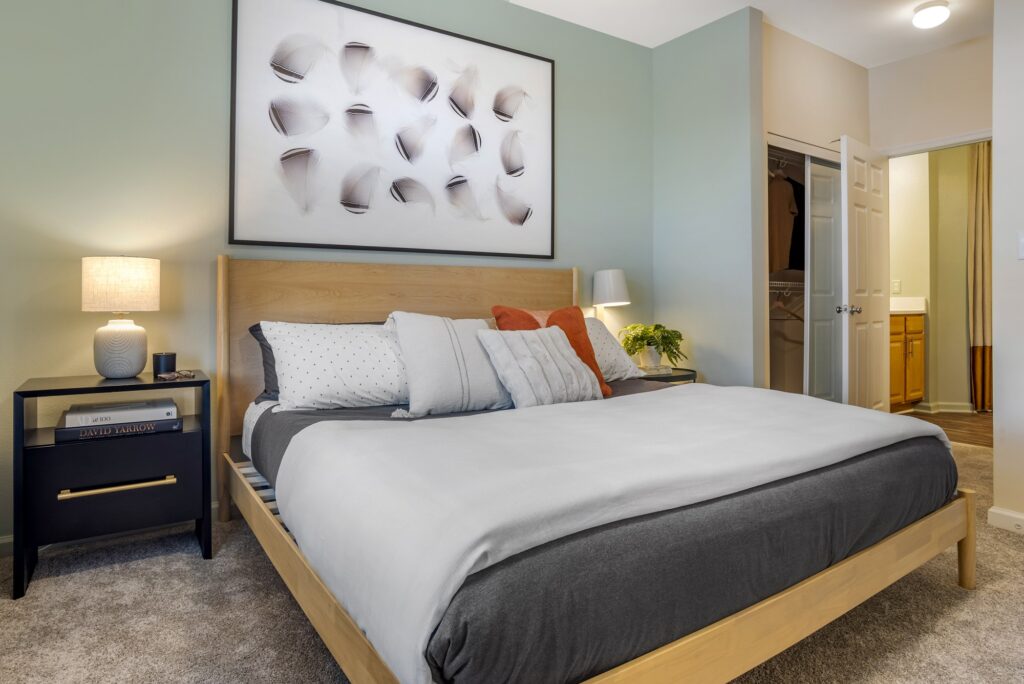 Bedroom with king size bed, accent colored walls, lamps, bathroom access, and carpet flooring