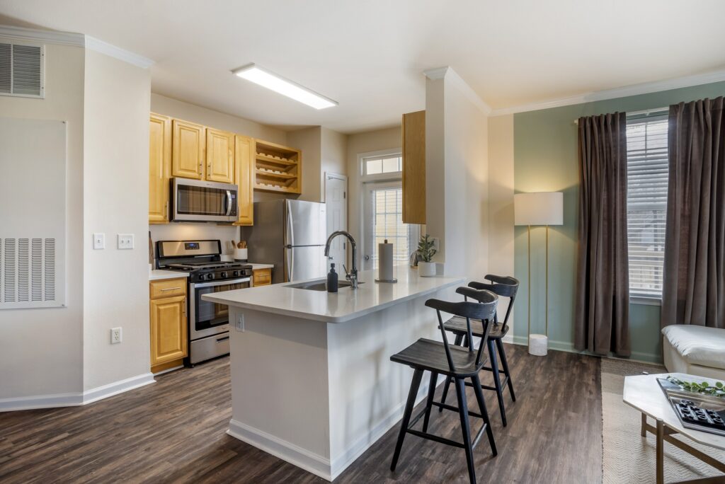 Kitchen area with island sink, stainless steel appliances, patio access, and wood-style flooring