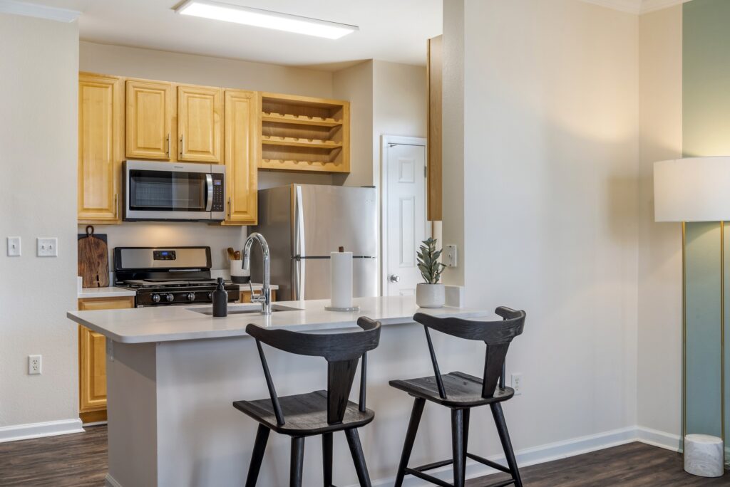 Kitchen area with island sink, stainless steel appliances, patio access, and wood-style flooring