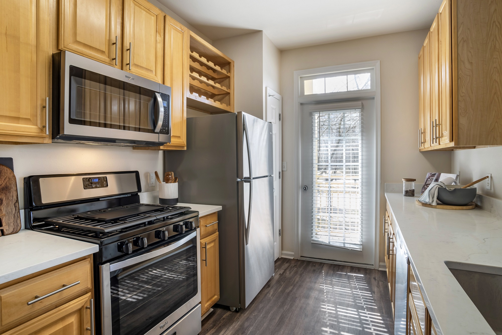 Kitchen area with stainless steel appliances, patio access, granite countertops, and wood-style flooring