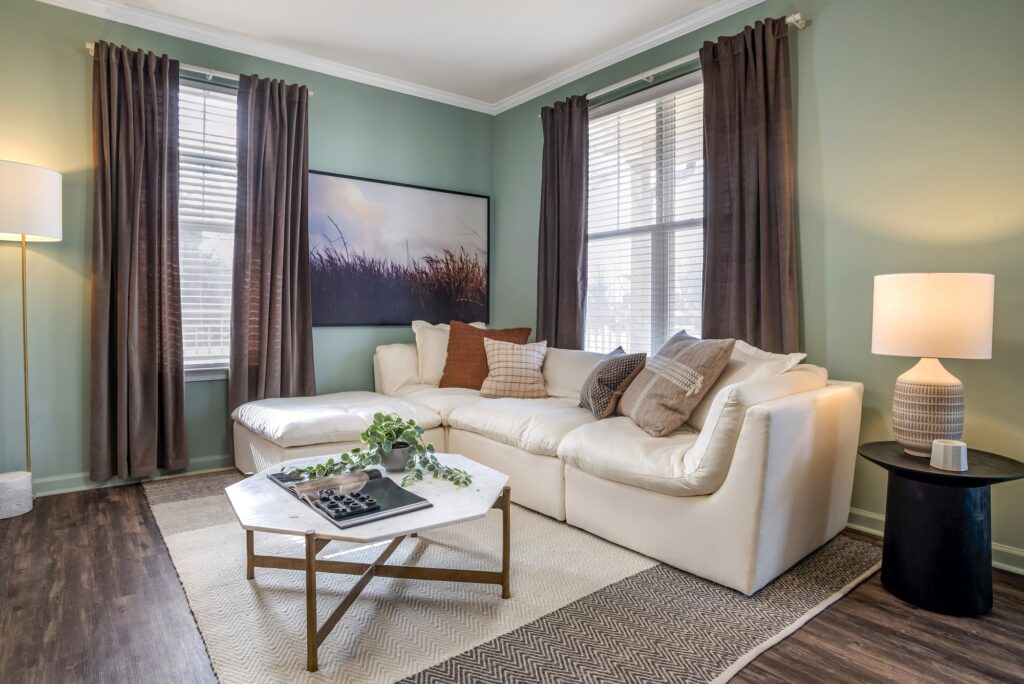Living room with couch, window lighting, accent colored walls, and wood-style flooring